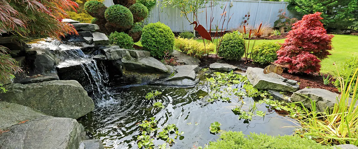 A beautiful pond building in Pensacola with a waterfall in a backyard