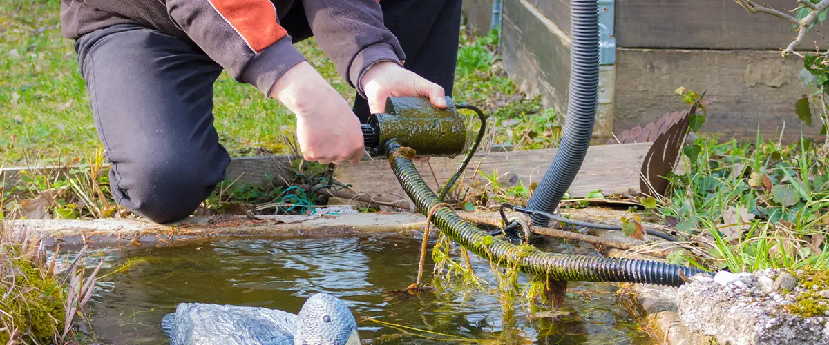 Contractor cleaning pond water filter