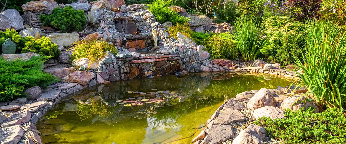 A pond with a waterfall with rocks